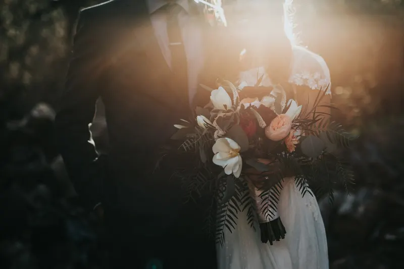 Bride and groom holding a bouquet in warm evening light